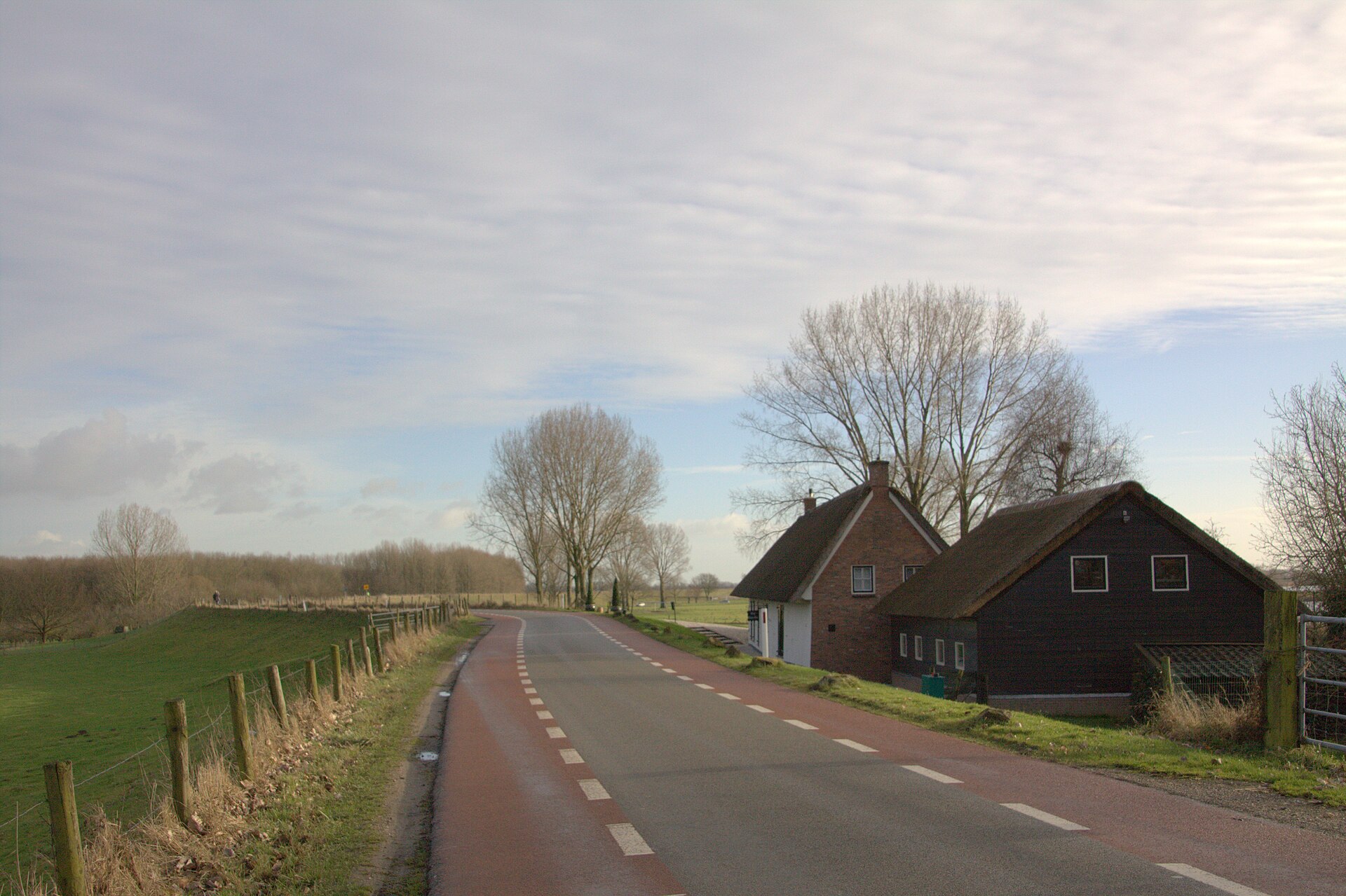 Weg over de Lekdijk bij Tull en ’t Waal, met een grasbegroeid talud en het voormalige tolhuis. Illustratief beeld.